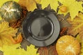 Autumn Halloween or thanksgiving day table setting. Fallen maple leaves, pumpkins, physalis. empty black plate on wooden Royalty Free Stock Photo