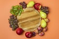 Autumn Harvest Card or Background Various Fruits Grapes Apples Plum and Pears Laying Round Wooden Tray Orange Background Top View