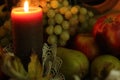 Autumn harvest still life. Cozy house warmth. Candle flame and fruits composition: red apples, green pears and grapes Royalty Free Stock Photo