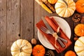 Autumn harvest or thanksgiving table setting with silverware, orange napkin, pumpkins and decor, top view corner border against wo