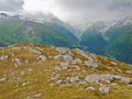 Autumn in high Alpine mountains. Dark peaks touch heavy misty clouds. Cold and damp end of the day in Alps