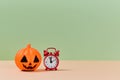 Autumn holiday. Halloween concept. Scary orange pumpkin and red clock. Copy space for text. Isolated on green backdrop