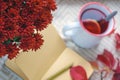 Autumn, home decor in the style of the Scandinavian Hygge. Fruit tea, red chrysanthemum and a notepad