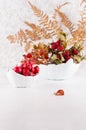 Autumn home decoration with red dried leaves rosehip, fern leaf, ripe berries hawthorn in bowl on white wood table, vertical. Royalty Free Stock Photo