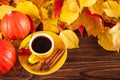 Autumn horizontal banner with yellow, red leaves, pumpkins, cup of coffee and guelder rose on brown wooden background. Royalty Free Stock Photo