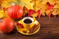 Autumn horizontal banner with yellow, red leaves, pumpkins, cup of coffee and guelder rose on brown wooden background. Royalty Free Stock Photo