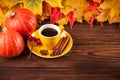 Autumn horizontal banner with yellow, red leaves, pumpkins, cup of coffee and guelder rose on brown wooden background. Royalty Free Stock Photo