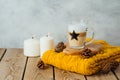 Autumn hygge concept with latte macchiato coffee cup, candles and sweater on wooden table