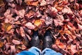 Autumn image of legs in black boots on the colorful leaves. Golden season.