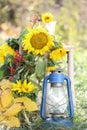 Autumn impression with sunflowers, yellow leaves, an old lantern and a vintage chair in a rural garden