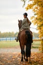 Autumn landscape, beautiful brunette girl with long hair posing with a red horse in the forest. Royalty Free Stock Photo