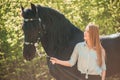 Beautiful brunette girl with long hair posing with a red horse in forest Royalty Free Stock Photo