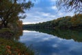 autumn landscape, beautiful sunset and bright colorful forest in the evening, trees near river and blue sky Royalty Free Stock Photo