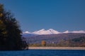 Autumn landscape with a blue lake and mountains in the background. Colorful forest at the edge of the water Royalty Free Stock Photo