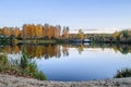 The Boat Shed on quiet colorful lake that reflects autumn leaves, blue sky with clouds