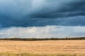 Autumn landscape with cloudy weather, large rainy clouds over a chamfered yellow field