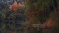 Autumn landscape, evening on the lake surrounded by colorful trees and reflections with a small pier Royalty Free Stock Photo