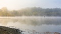 Autumn landscape with a fisherman on the lake in the fog. Early morning on the lake Royalty Free Stock Photo