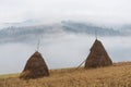 Autumn landscape with haystacks and fog in the mountains Royalty Free Stock Photo