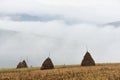 Autumn landscape with haystacks and fog in the mountains Royalty Free Stock Photo