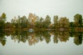 Autumn landscape. Lake, trees and village by the lake. Calm. Perfect reflection in the water. Royalty Free Stock Photo