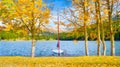 Autumn landscape on the lakeside. Trees with yellow leaves. A boat on the shore of a mountain lake. Natural landscape in autumn ti Royalty Free Stock Photo