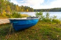 Autumn landscape, an old blue boat lies on the shore of a forest lake. The boat is pulled ashore for the winter for safety Royalty Free Stock Photo