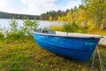 Autumn landscape, an old blue boat lies on the shore of a forest lake. The boat is pulled ashore for the winter for safety Royalty Free Stock Photo