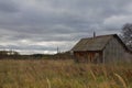 Autumn landscape with an old ruined wooden house. Old house in a field in the village on a cloudy day Royalty Free Stock Photo