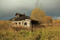 Autumn landscape with an old ruined wooden house. Old house in a field in the village on a Sunny day Royalty Free Stock Photo