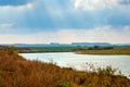 Autumn landscape with river and sunbeam breaking through clouds