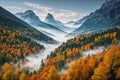 Autumn landscape - view of a wooded river valley with morning fog surrounded by snowy mountains Royalty Free Stock Photo