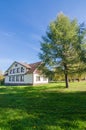 Autumn landscape with white holiday cottage, lawn and pine with blue sky background. Near the house there are bicycles Royalty Free Stock Photo