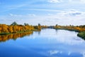 Autumn landscape, yellow leaves trees on river bank on blue sky and white clouds background on sunny day, reflection in blue water Royalty Free Stock Photo