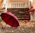 Autumn leaf fall. Red and yellow leaves on the destroyed old stone steps burgundy (marsala color) umbrella. Royalty Free Stock Photo