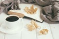 Autumn leaves, cup of coffee, warm wool sweater with open old book on white rustic wooden boards. Cozy home reading, hygge concept Royalty Free Stock Photo
