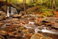 Autumn leaves fall around a babbling brook and waterfall Royalty Free Stock Photo