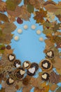 Autumn leaves frame with dry citrus fruits slices of oranges and mandarins and wooden hearts on blue paper background