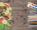 Autumn leaves paints pencils and brushes on wooden background Royalty Free Stock Photo