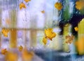 Autumn leaves  and rain drops  on window glass  cold rainy season   on street  bokeh blurred city evening light reflection urban s Royalty Free Stock Photo