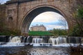 Autumn light gilds a historic stone arch over a rushing cascade Royalty Free Stock Photo