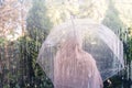 Autumn. Lonely muslim woman in a headscarf under a transparent umbrella. View through a window with raindrops. Rainy day.