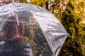 Autumn. Lonely sad woman under a transparent umbrella with rain drops walking in a park, garden. Rainy day landscape. Royalty Free Stock Photo