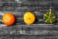 Autumn minimalistic composition with orange, yellow and green pumpkins on dark wooden background. top view