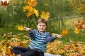 Autumn mood. The boy throws yellow maple leaves. Autumn portrait of a child in yellow foliage. Sight. A sweet, caring boy Royalty Free Stock Photo