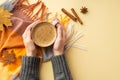 Autumn mood concept. First person top view photo of woman`s hands in sweater holding cup of frothy coffee over plaid scarf Royalty Free Stock Photo