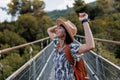 autumn mood. A female tourist walks along the bridge over the river. A young woman walks along a suspension bridge across a river Royalty Free Stock Photo