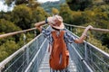 autumn mood. A female tourist walks along the bridge over the river. A young woman walks along a suspension bridge across a river Royalty Free Stock Photo