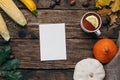 Autumn mood: present card, pumpkins and corn with yellow leaves on a wooden background