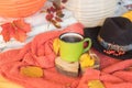 Autumn mood-warm red sweater, hat and a cup of hot coffee in the framing of autumn leaves which turn into the warm colors of